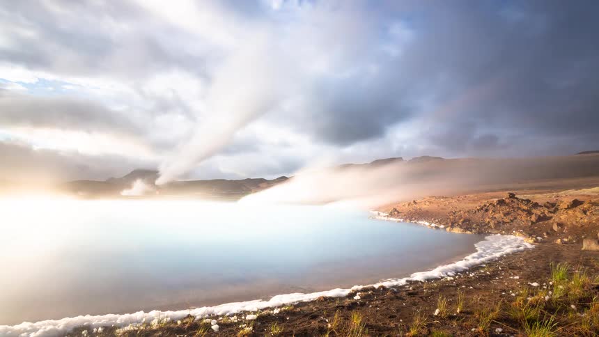 A stunning timelapse captures steam rising from a milky blue geothermal lagoon as the sun breaks through dramatic, fast-moving clouds in Iceland