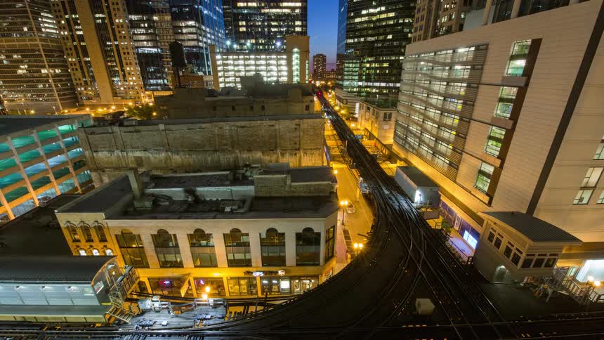 A stunning night timelapse captures the constant motion of Chicago's elevated trains weaving through the brightly lit urban canyon of skyscrapers