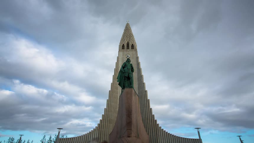 A dramatic timelapse captures clouds moving swiftly over the iconic Hallgrímskirkja church and Leif Erikson statue in Reykjavik, Iceland