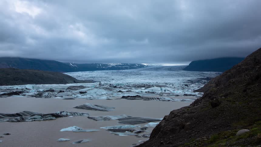 A dramatic timelapse captures clouds moving over a vast glacier and its lagoon filled with icebergs in Iceland