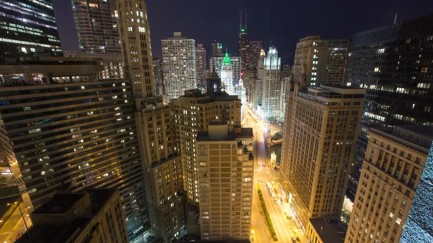 An elevated timelapse captures the transition from dusk to night over the bustling streets and towering skyscrapers of downtown Chicago