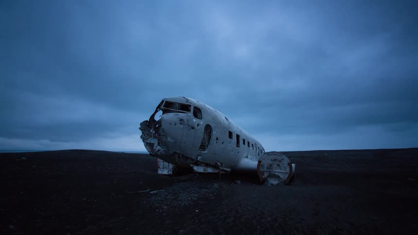 Dramatic time-lapse of the iconic Sólheimasandur plane wreck on a black sand beach under a dark, cloudy sky in Iceland