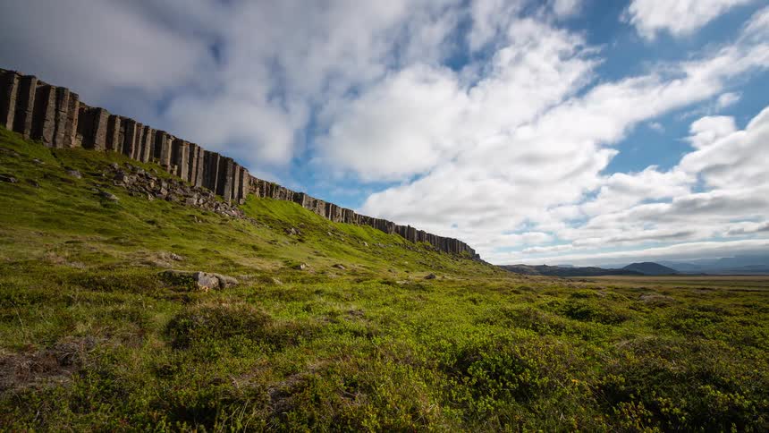 A dramatic timelapse shows clouds speeding over the iconic Gerðuberg basalt columns in Iceland's vast green landscape