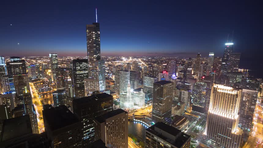 Time-lapse of the iconic Chicago skyline at twilight as the city lights illuminate the towering skyscrapers and busy streets below
