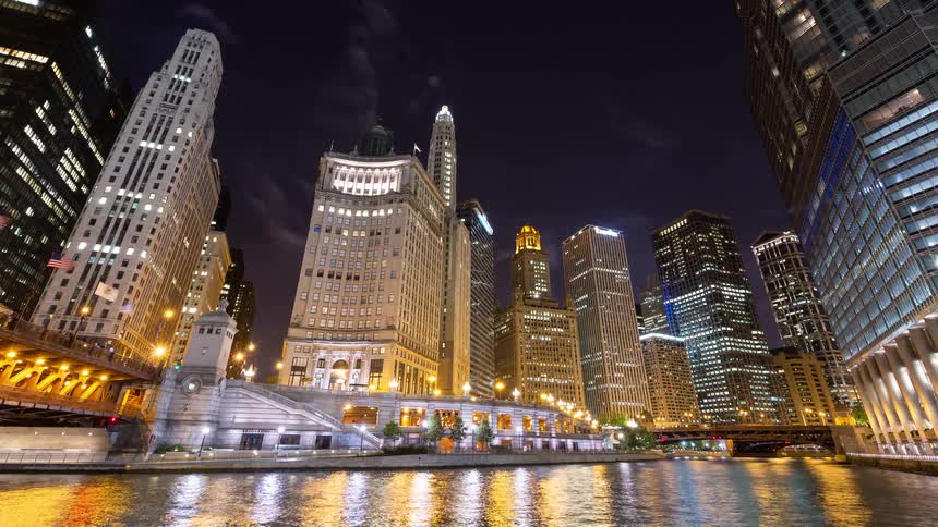 Vibrant timelapse of the bustling Chicago River at night, with tour boats passing by the illuminated city skyline