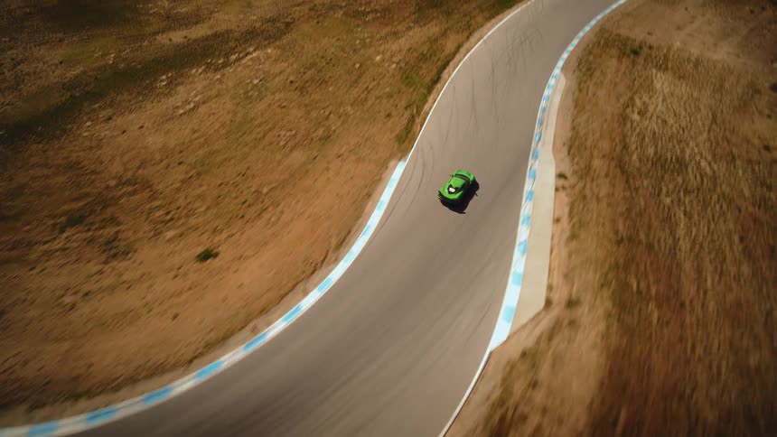 An exhilarating high-angle aerial view captures a green sports car racing at high speed around a winding track