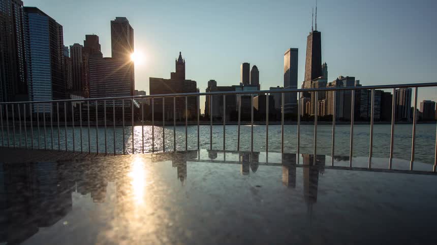 A reflective timelapse captures the sun rising over the iconic Chicago skyline from across Lake Michigan