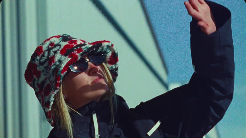 Slow motion close-up of a stylish woman in a fluffy bucket hat and sunglasses shielding her face from the sun