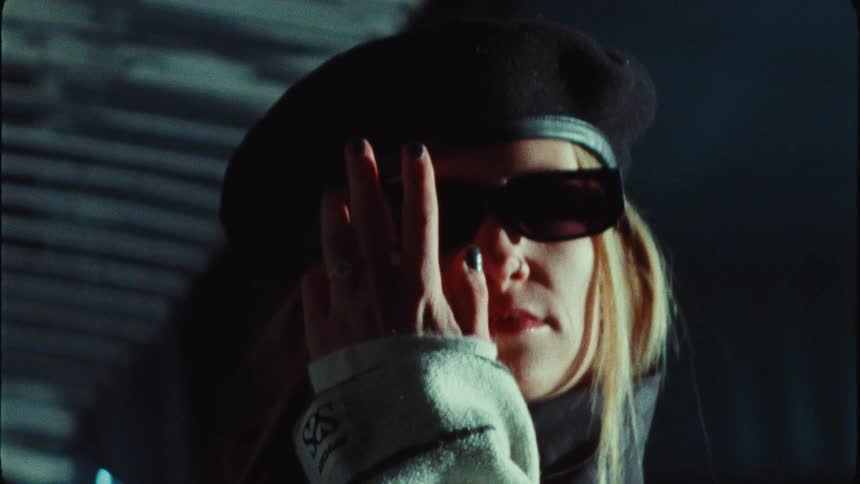 Cinematic close-up of a stylish blonde woman in a black beret and sunglasses posing mysteriously for the camera