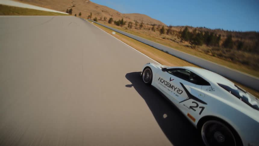 A sleek white Corvette race car carves through corners and accelerates down the straightaways of a scenic track on a sunny day