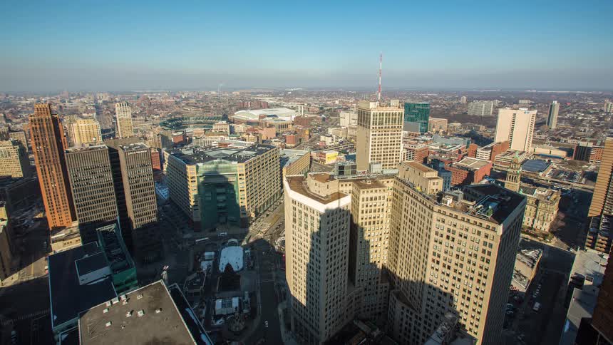 A sunny daytime timelapse over the bustling city of Detroit, Michigan, as long shadows from skyscrapers move across the streets