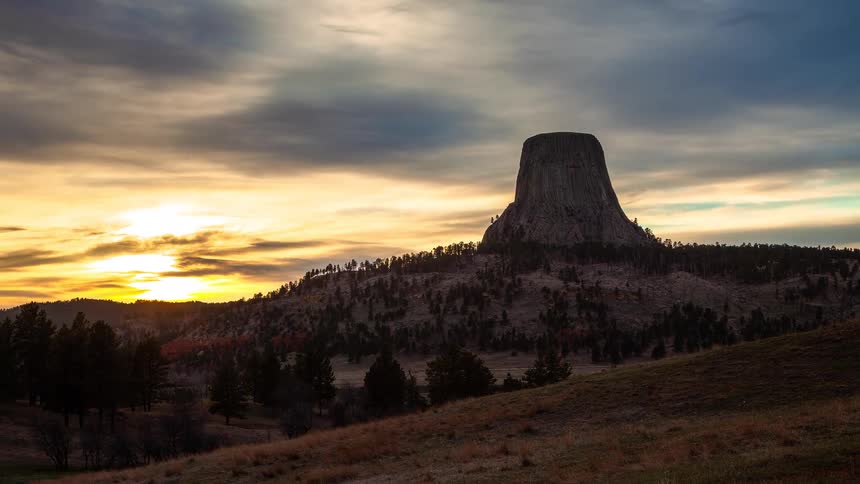 A beautiful timelapse captures a colorful sunset behind the silhouette of Devils Tower National Monument in Wyoming