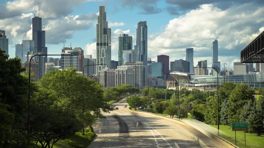 A vibrant timelapse of the Chicago skyline on a sunny day, with blurred traffic on the highway and clouds rolling overhead