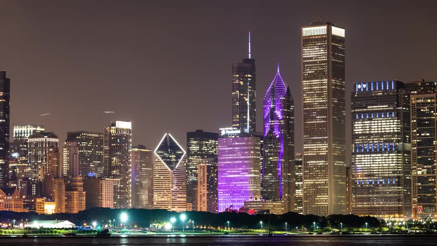 Timelapse of the vibrant Chicago skyline illuminated with purple lights at night as seen from across the water
