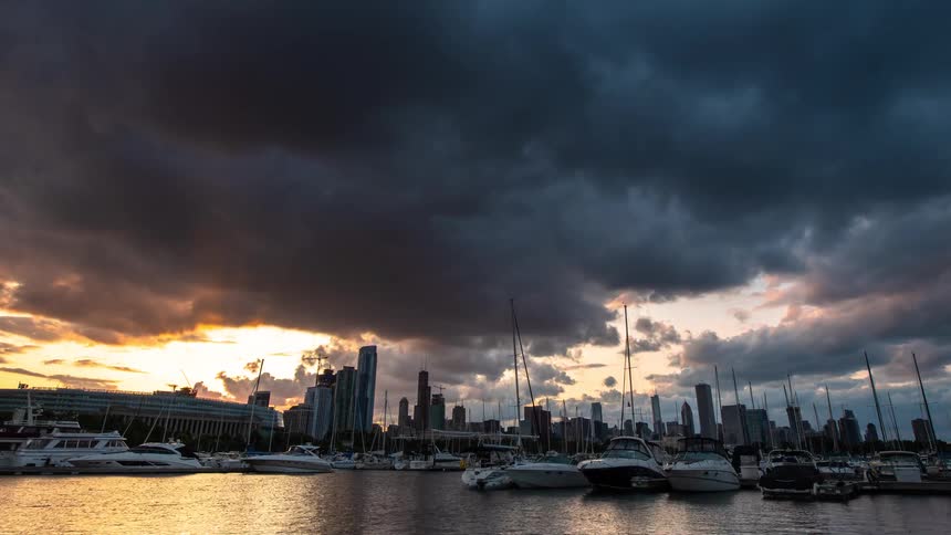 A dramatic day-to-night time-lapse shows storm clouds rolling over a busy city harbor as the sun sets and the skyline lights up