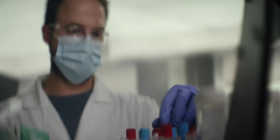A medical researcher wearing protective gear meticulously analyzes blood samples in a laboratory