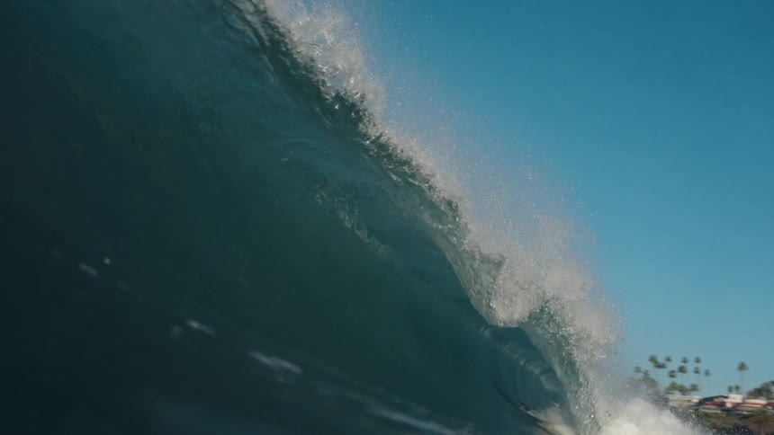 A slow motion close-up of a powerful ocean wave cresting and breaking as seen from the water's surface