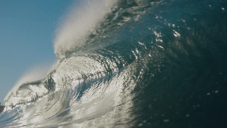 Slow motion footage from inside a powerful ocean wave as it barrels and breaks, plunging the view underwater
