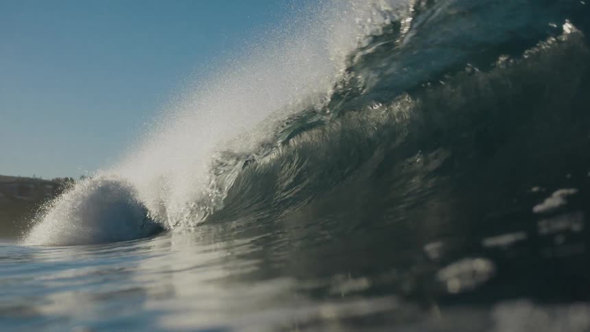 Sunlight glistens on a perfect ocean wave as it curls and breaks in stunning slow motion, ending with an underwater view