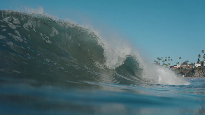 An up-close, slow-motion view from the water as a powerful ocean wave curls and breaks towards the shore