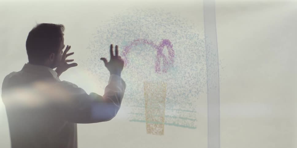 A researcher in a lab coat manipulates a vibrant digital brain diagram on a large touchscreen display