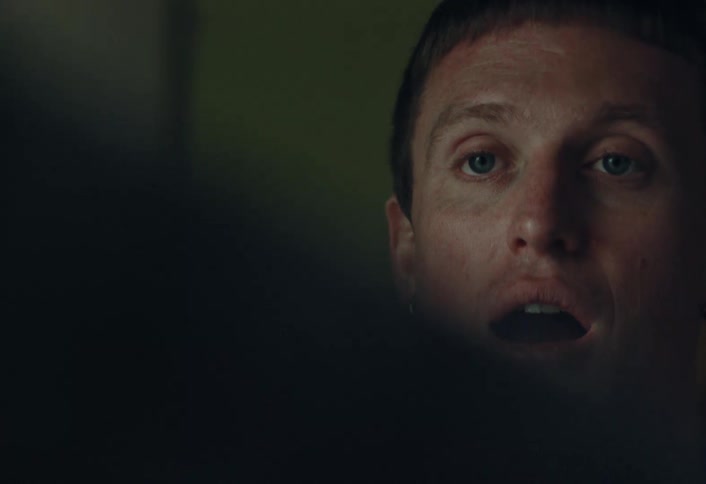 An over-the-shoulder close-up captures a man's expressive face as he reacts with joy and amazement