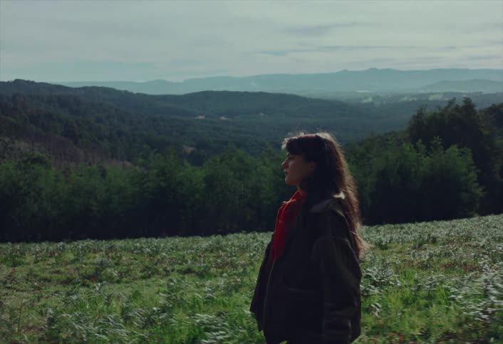 A young couple walks side-by-side through a picturesque mountain landscape on a cloudy day