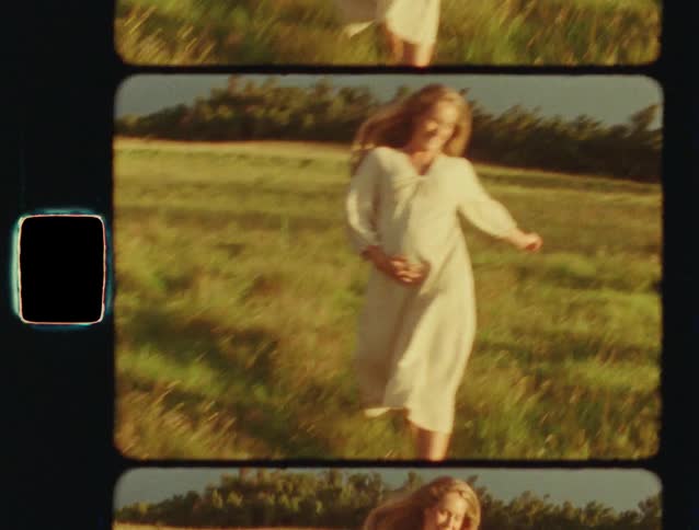 Vintage Super 8 film of a beautiful pregnant woman in a white dress smiling and dancing in a golden field