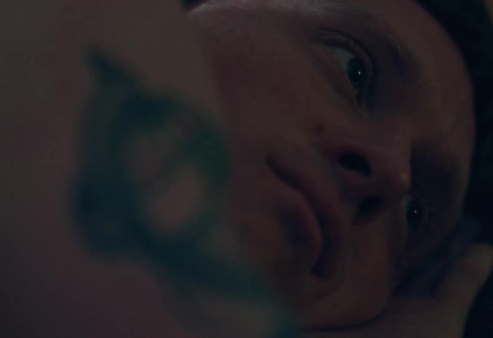 An intimate and moody close-up captures a person wincing in emotional distress while lying in the dark