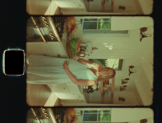 A happy pregnant woman eats watermelon and rubs her belly in a bright, sunny kitchen, captured in a vintage film style