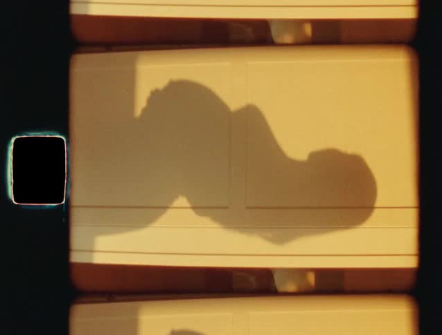 A vintage 35mm film scan shows the shadow of a person resting and shifting in the warm sunlight