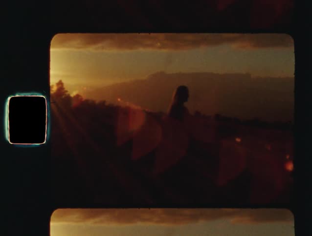 A silhouetted woman practices tai chi on a mountain at sunset in this vintage-style 8mm film footage