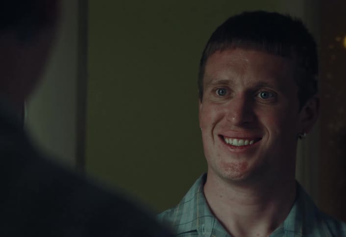 A young man's happy smile slowly changes into a mischievous and playful smirk as he listens to someone off-camera
