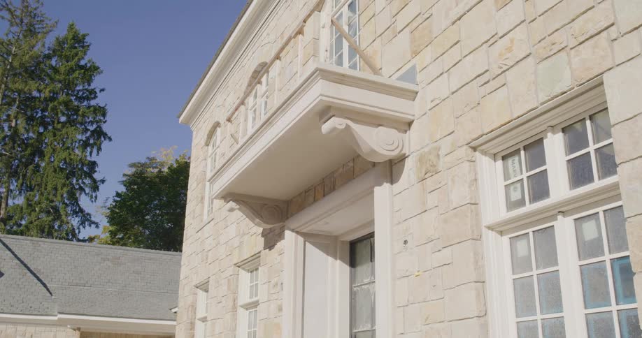 Slow pan up the beautiful stone facade and ornate architectural details of a new luxury home under construction