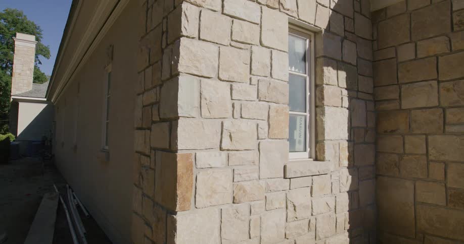 A slow pan reveals the beautiful exterior stonework and stucco of a luxury home during its construction phase