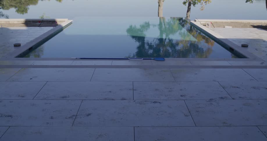A stunning infinity pool overlooks a vast lake on a clear day, with the camera slowly moving down