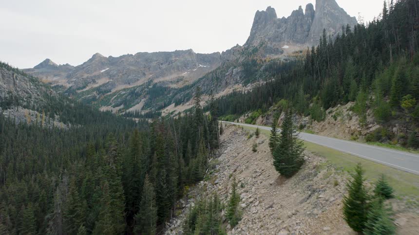 Aerial view of a white SUV driving on a winding road through the stunning North Cascades mountains in Washington State