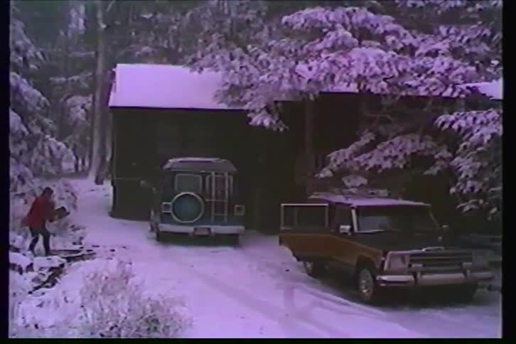 Vintage VHS footage captures a serene snow day with a classic Jeep Wagoneer parked at a wooded cabin