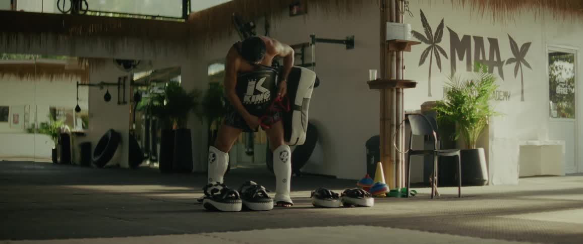 A focused MMA fighter prepares for training by tying on his protective belly pad inside a gym