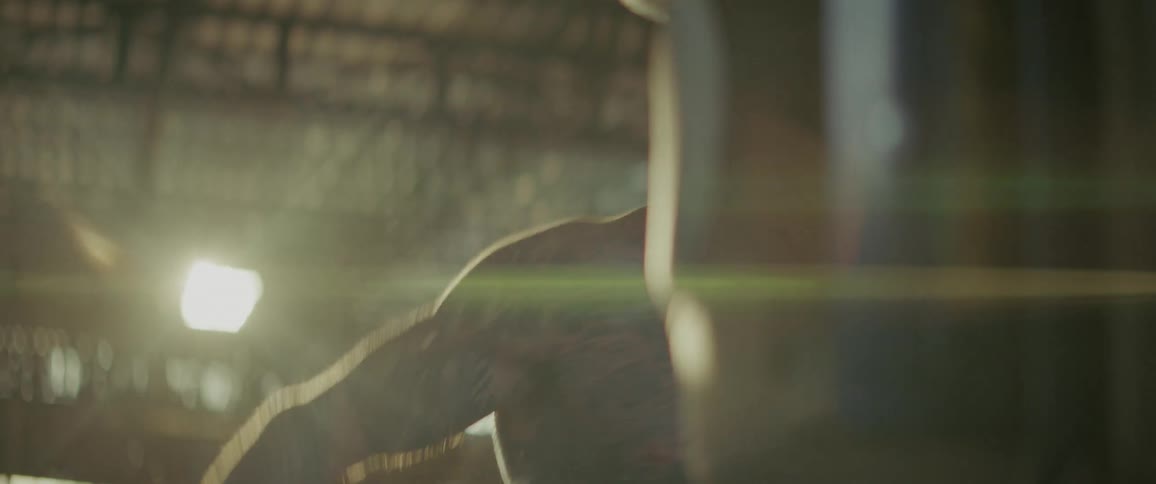 An intense tattooed fighter with a beard sweats as he powerfully strikes a punching bag in slow motion