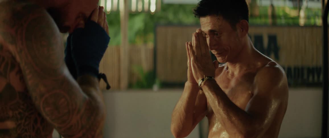 Two sweaty Muay Thai fighters show mutual respect with a traditional bow and handshake after a training session