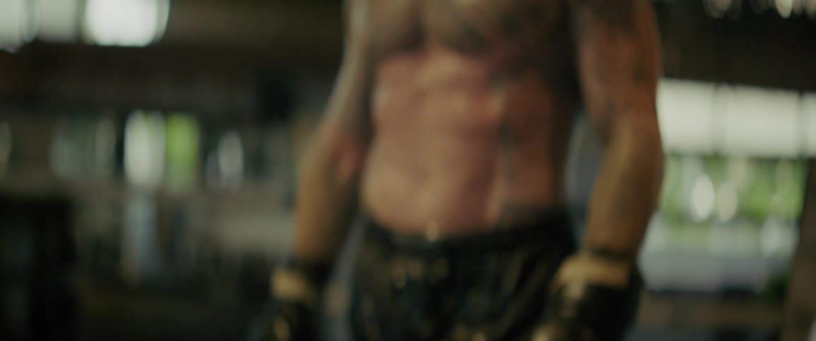 Slow motion close up of a tough, tattooed, and bearded fighter catching his breath after a difficult training session