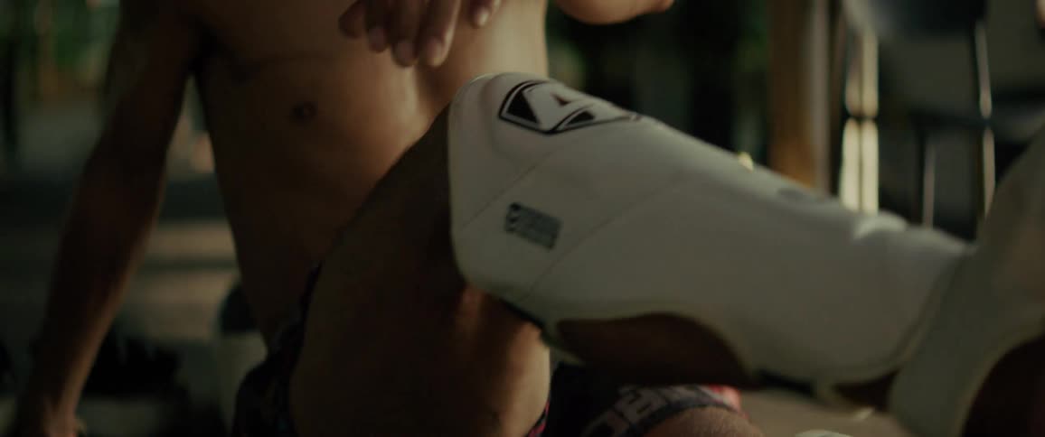 Slow motion close-up of a shirtless Muay Thai fighter resting and looking off-camera after training
