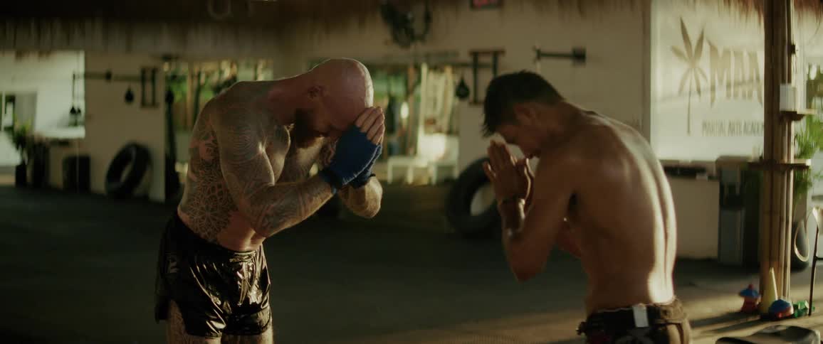 Two muscular fighters show respect and camaraderie, bowing to each other and hugging after a friendly sparring session in a gym