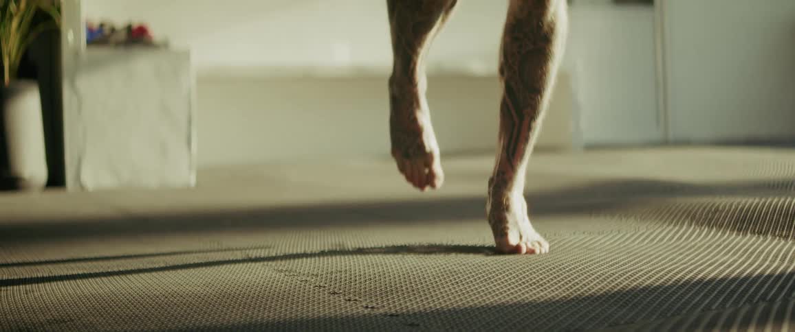 A tattooed and bearded MMA fighter intensely skips rope in slow motion during a grueling workout at a tropical gym