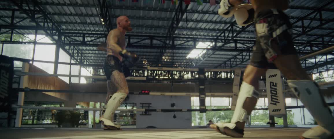 Two powerful Muay Thai fighters spar in a boxing ring until one delivers a dramatic takedown in super slow motion