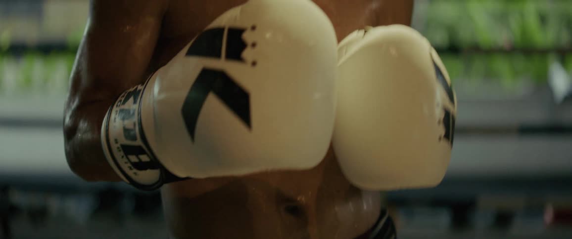 Slow motion close-up of a determined and sweaty male boxer breathing heavily while training in a boxing ring