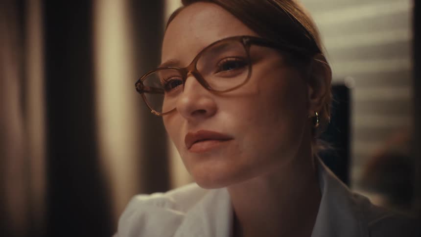 Rack focus shot of a female scientist in a lab coat examining a specimen on a glass slide with intense focus