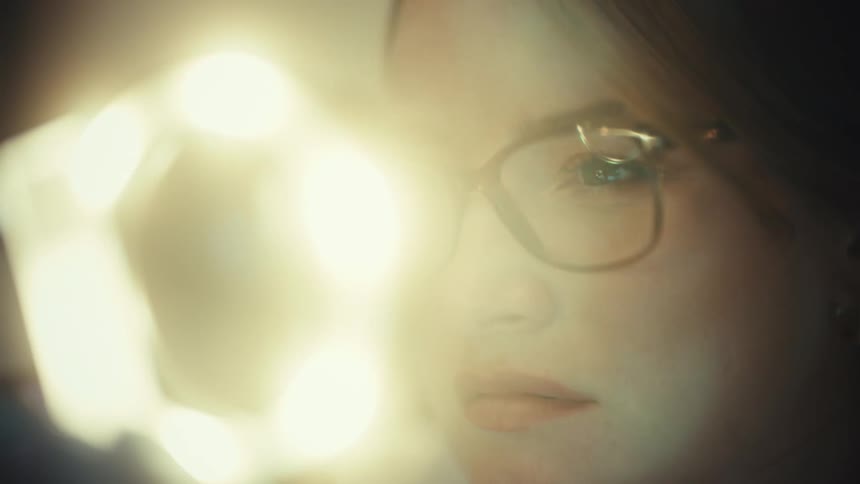 A female researcher turns on a bright ring light on her magnifying equipment for close inspection