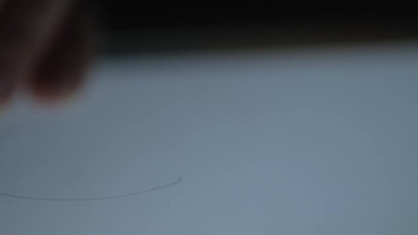 Macro shot of a mechanical pencil tip drawing a fine curved line on a brightly lit surface in slow motion
